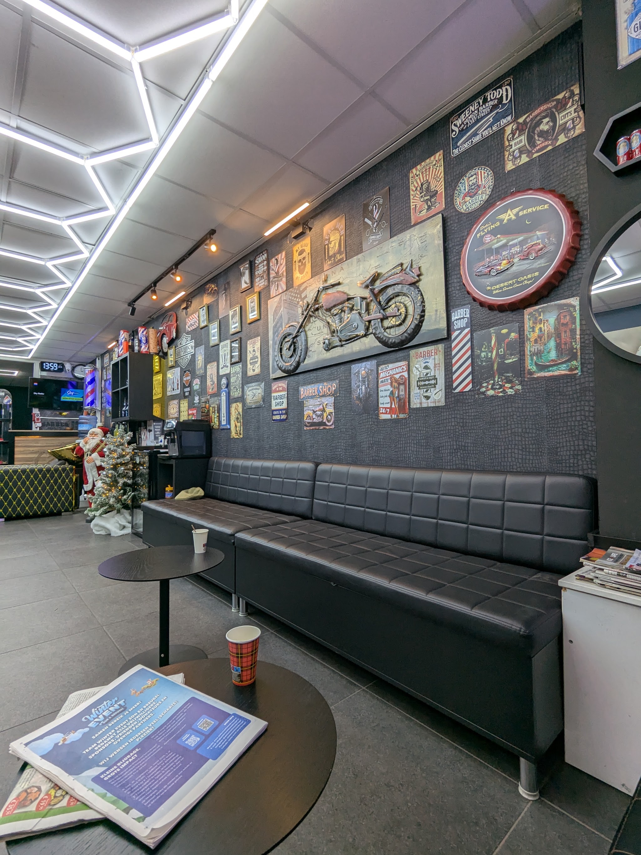 De wachthoek met een lange leren bank, een koffietafel en een wand vol oude reclameborden